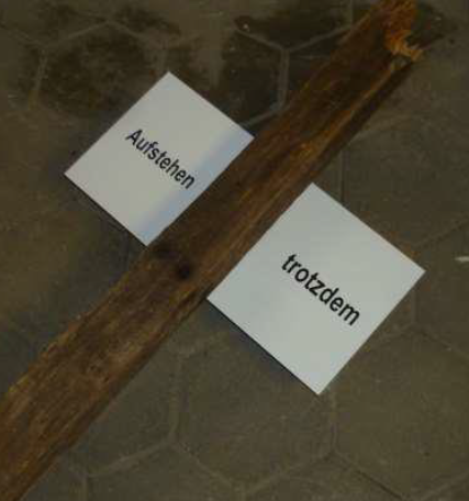 Holzpfosten mit einem Schild mit den Worten 'Aufstehen' und 'trotzdem'